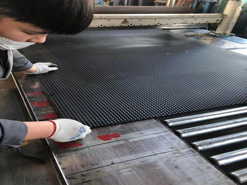 Un technicien effectue un contrôle de qualité sur une feuille de revêtement de sol en caoutchouc.